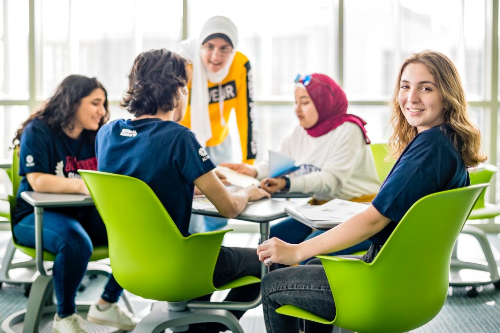 AUBH: students in Class of ’23 shirts studying together at a library table, creative direction by Bashar Daas