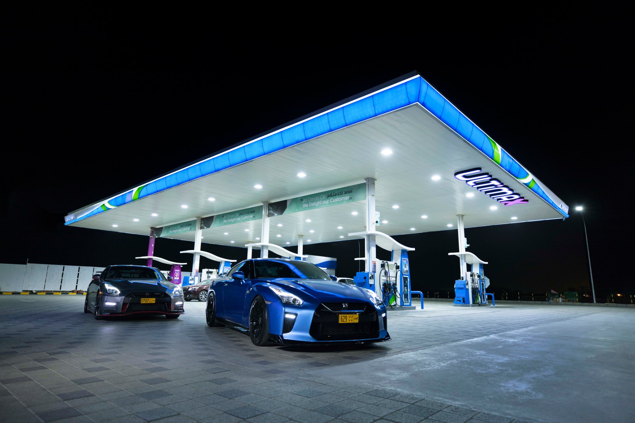 OOMCO: an OOMCO station lit up at night with sports cars at the pumps, creative direction by Bashar Daas