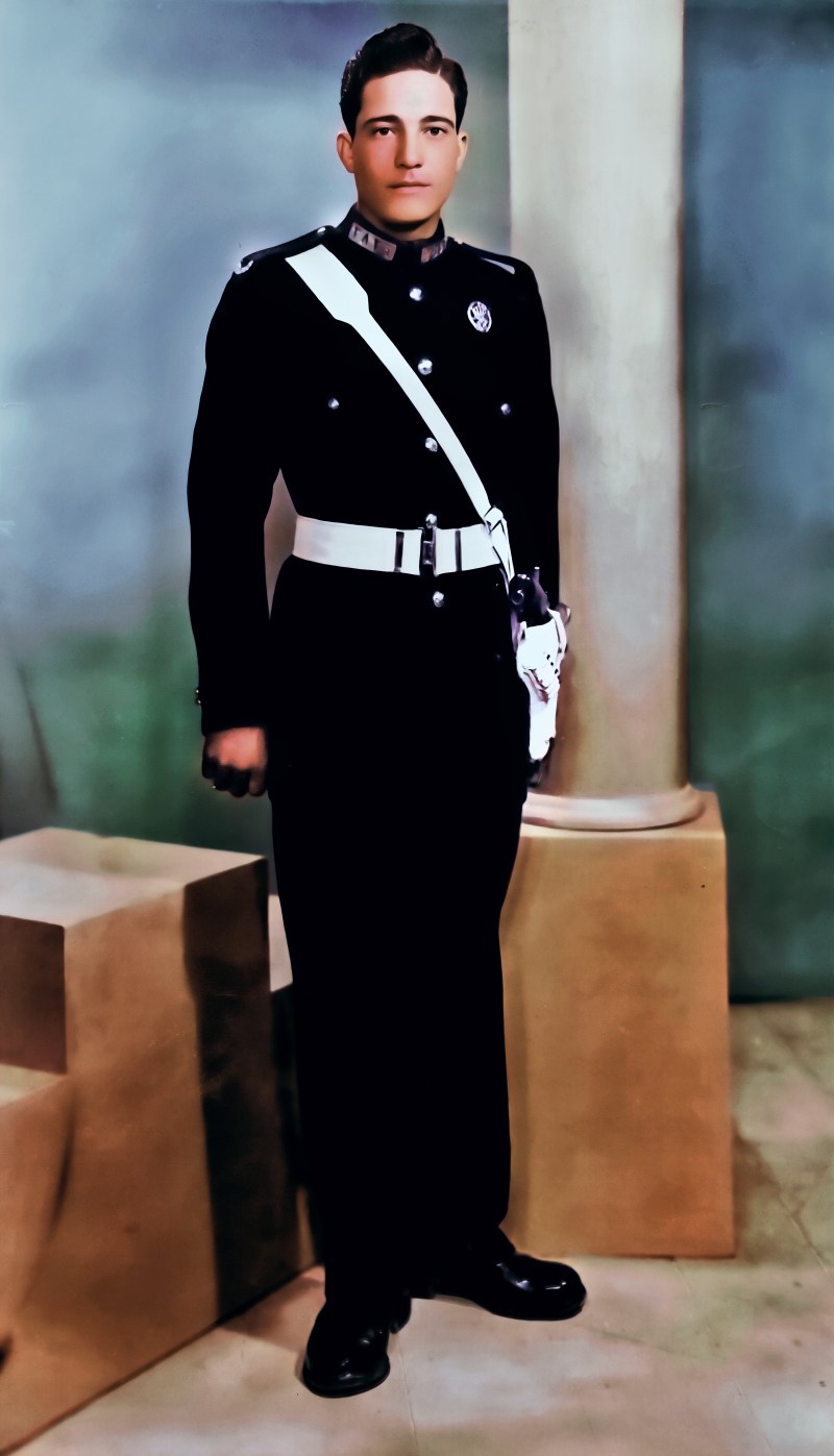 The portrait in colour: a dark uniform with a white cross-belt, warm skin tones and a blue-green studio backdrop