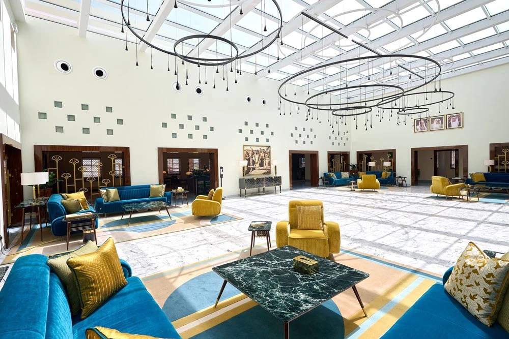 Awal Private Aviation Terminal: the main lounge under a glass roof, with circular ring chandeliers above blue and yellow seating