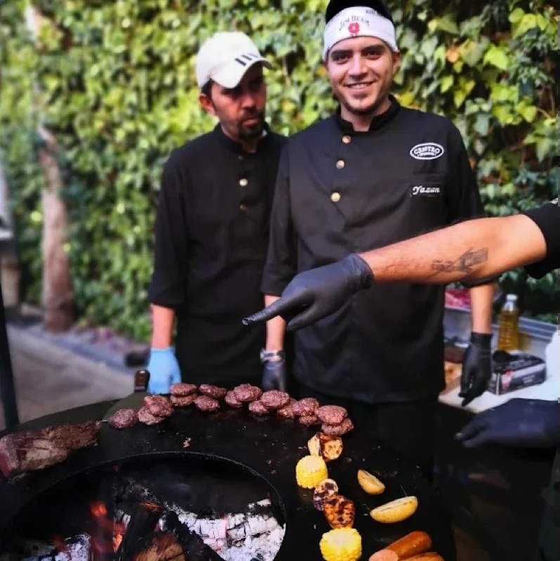 Centro Brasserie: chefs in black jackets with the oval logo, grilling over an open fire on the terrace, creative direction by Bashar Daas