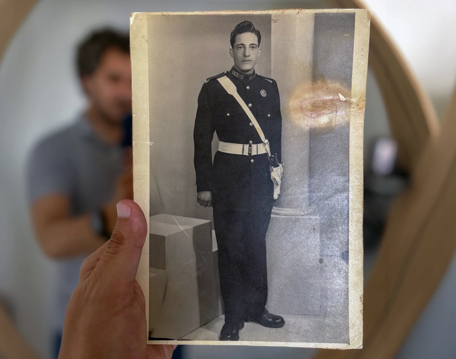 The original photograph of Bashar Daas's grandfather in his police academy uniform, held up in front of a mirror