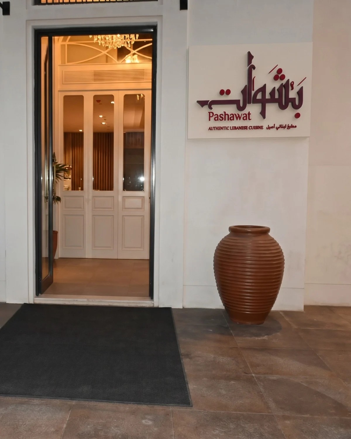 Pashawat: the maroon logo sign beside the restaurant entrance, with a clay pot by the door, brand identity by Bashar Daas